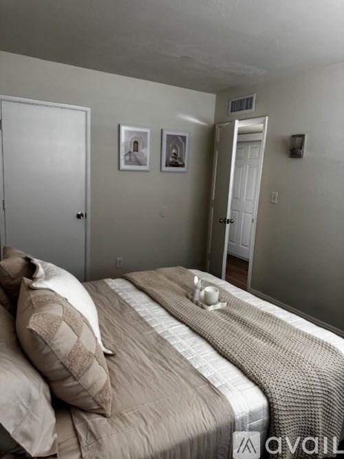 A bedroom with a bed, two pillows, a blanket, and two pictures on the wall.