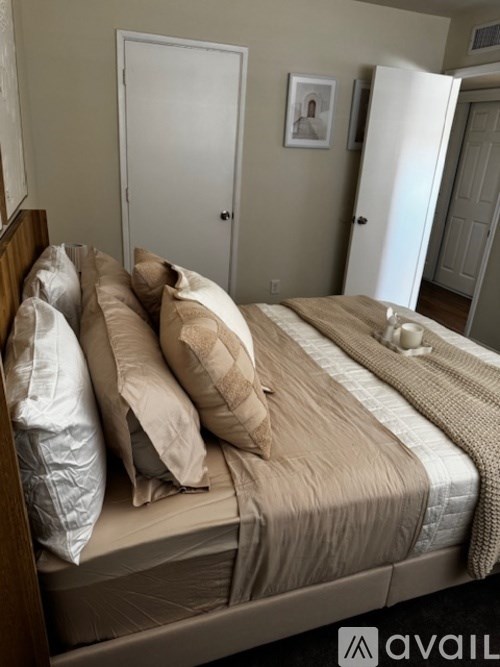 A bed with a brown comforter and pillows in a room with a white door.