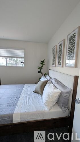 A bedroom with a bed, pillows, and pictures on the wall.