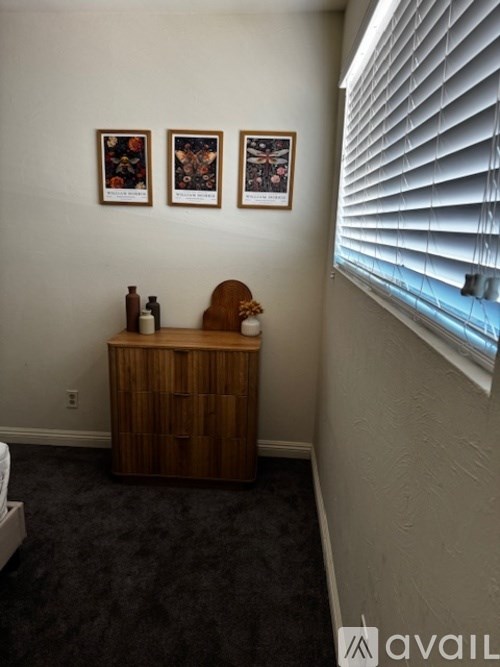 A room with a wooden cabinet and three pictures on the wall.