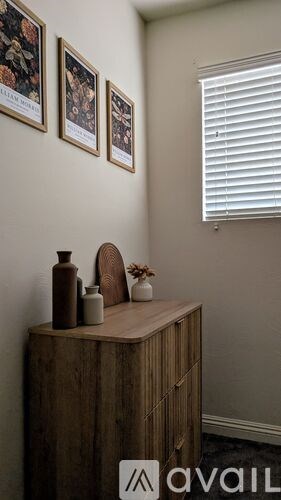 A wooden cabinet with a few items on top of it and three pictures hanging on the wall above it.