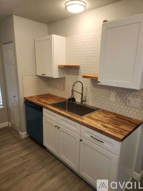 A kitchen with white cabinets and a wooden counter top.