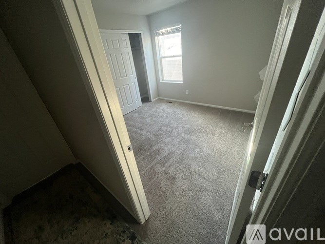 A carpeted room with a door and a window.