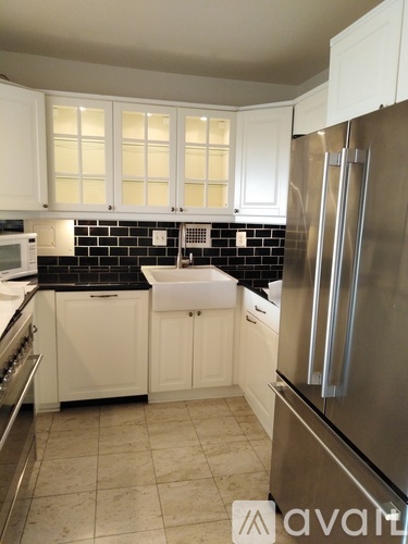 A kitchen with white cabinets and a black backsplash.
