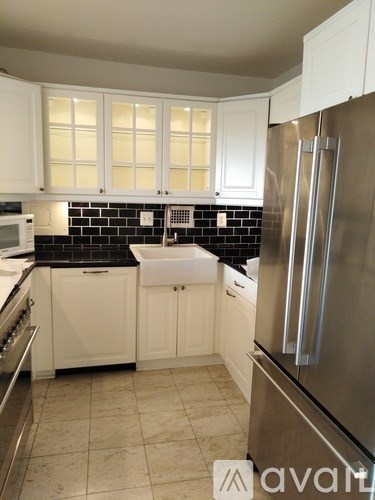 A kitchen with white cabinets and a black backsplash.
