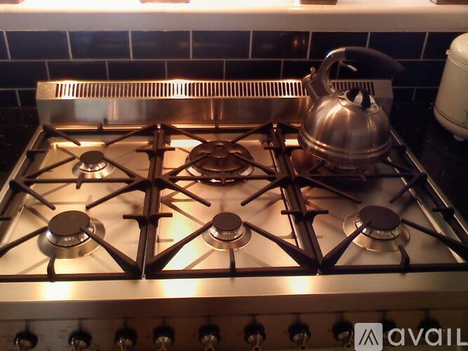A silver gas stove with a kettle on it.