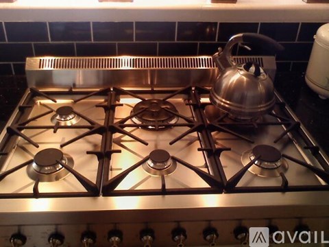 A silver gas stove with a kettle on it.