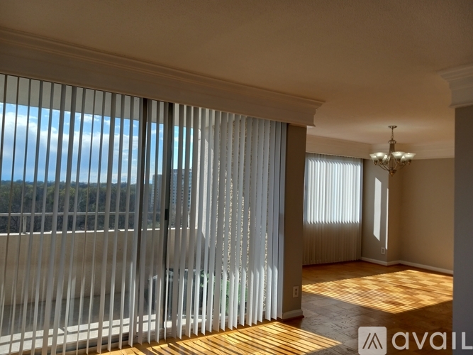 A room with a view of the ocean through the window with blinds.