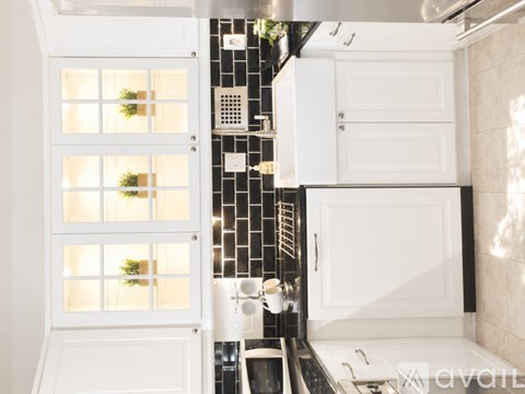A kitchen with white cabinets and a black and white tiled backsplash.