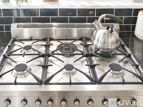 A stainless steel gas stove with a kettle on it.
