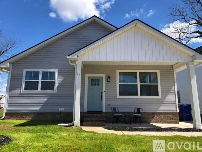A house with a grey siding and a white door is for sale.