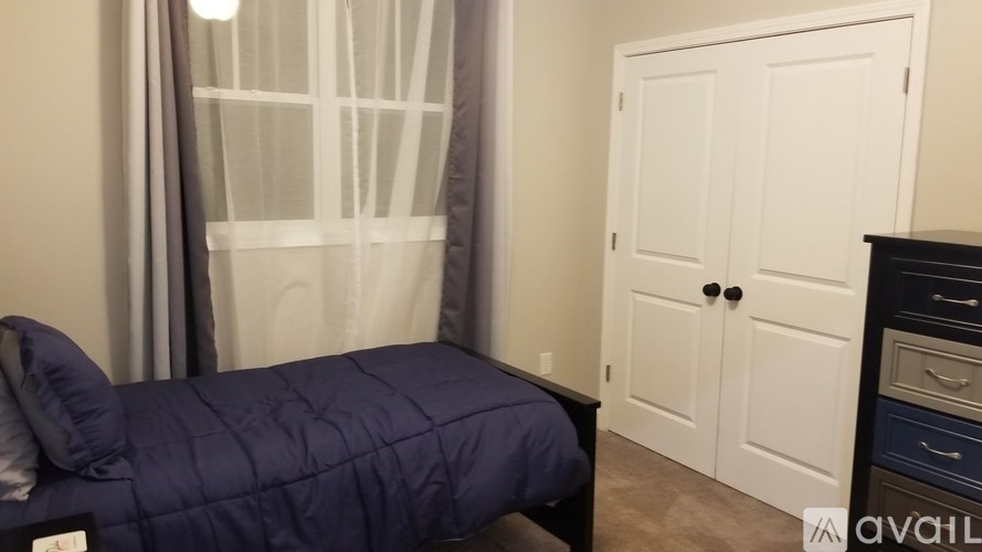 A bedroom with a bed covered in a blue comforter.