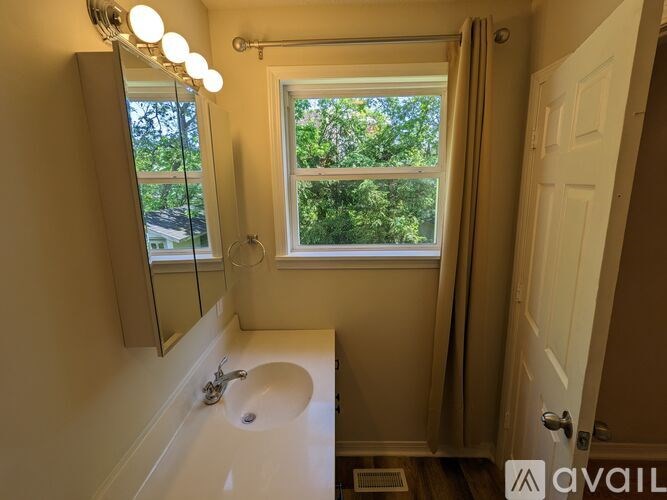 A bathroom with a sink, mirror, and window.