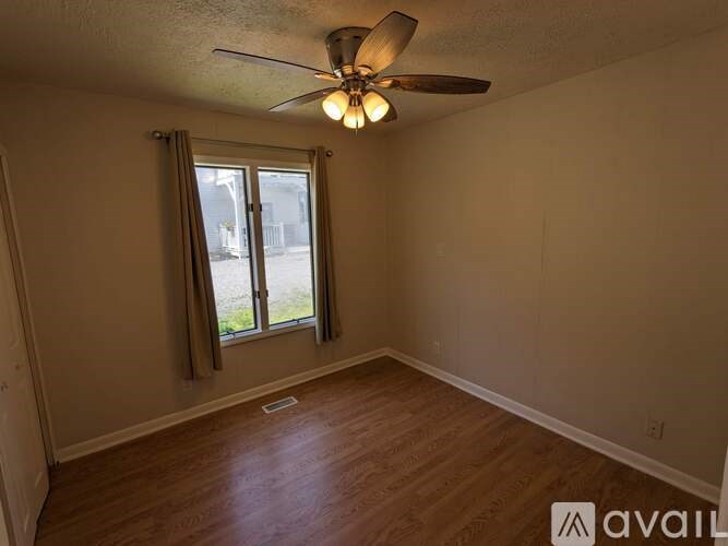 A room with a ceiling fan and a window with curtains.