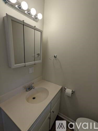 A bathroom with a sink, mirror, and light.