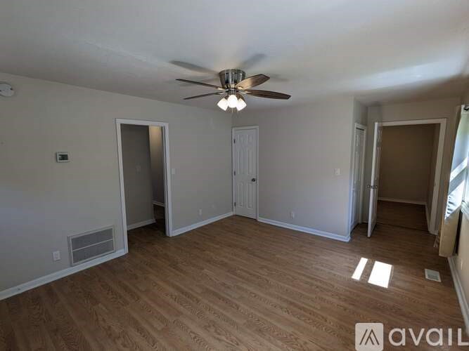 A room with a ceiling fan and wooden flooring.