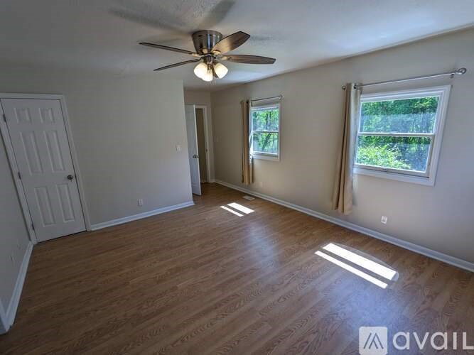 A room with a ceiling fan and wooden flooring.