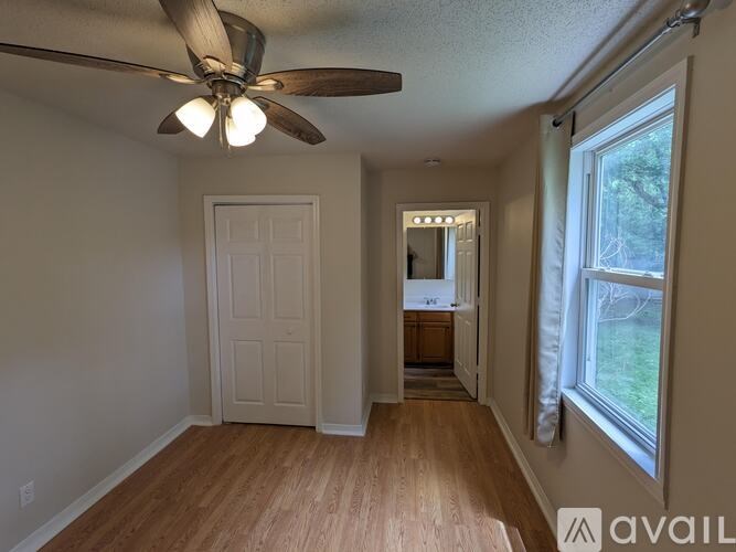 A room with a ceiling fan and wooden flooring.