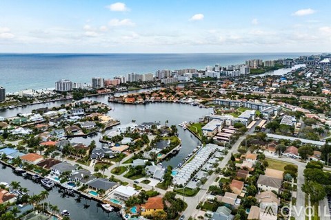 A view of a residential area with a body of water in the foreground and a city skyline in the background.
