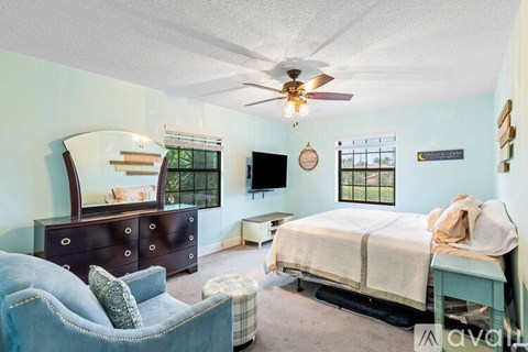 A bedroom with a bed, dresser, and chair.