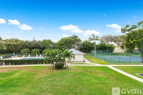 A tennis court surrounded by a green lawn and trees.