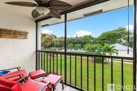 A balcony with a ceiling fan and a view of a green lawn and trees.