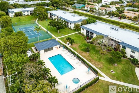A tennis court is surrounded by a pool and a tennis court building.