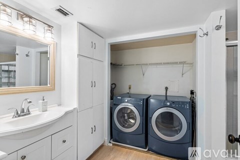 A laundry room with a sink, mirror, and two washing machines.