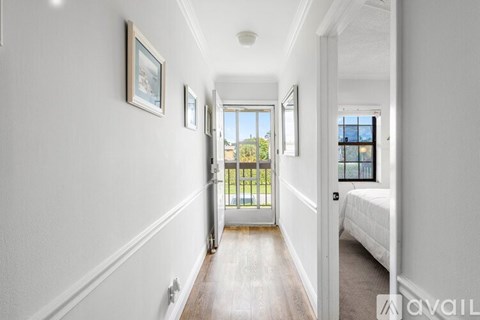 A hallway with a bedroom at the end and a balcony outside.