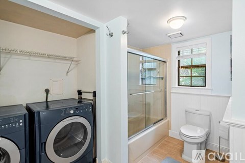 A laundry room with a washer and dryer, a toilet, and a bathtub.