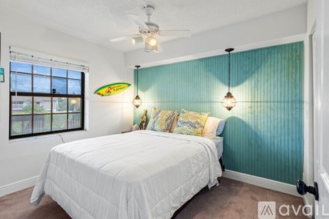 A bedroom with a white bed and a ceiling fan.