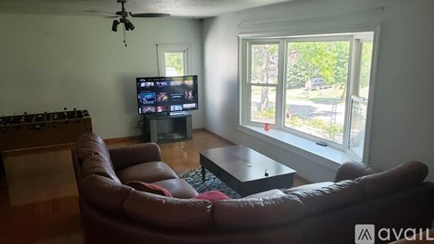 A living room with a brown leather couch and a television.