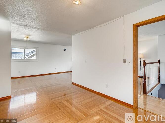 A spacious room with wooden flooring and white walls.