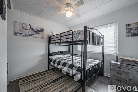 A bedroom with a black metal bunk bed and a dresser.