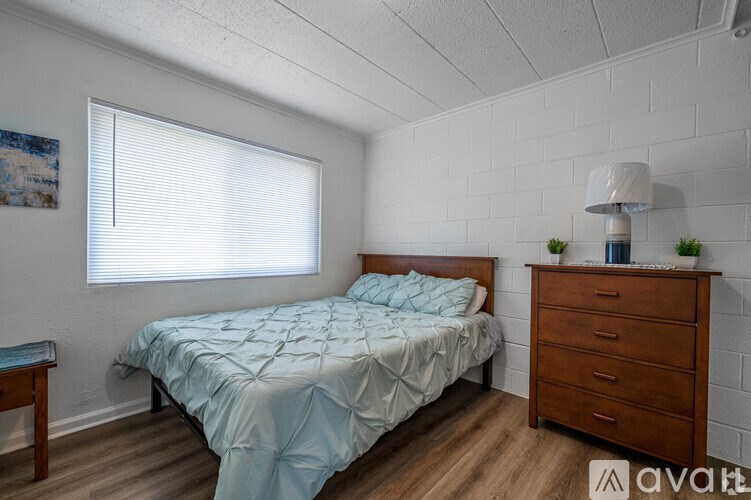 A bedroom with a bed, nightstand, and lamp.