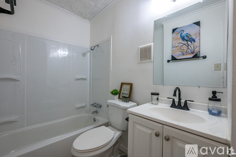 A bathroom with a white toilet, sink, and a painting of a bird on the wall.