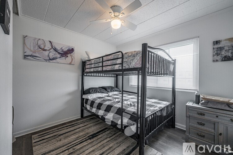 A bedroom with a black metal bunk bed and a dresser.