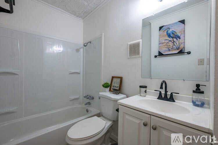 A bathroom with a white toilet, sink, and a painting of a bird on the wall.