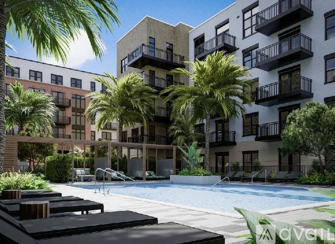 A pool surrounded by palm trees and lounge chairs in front of apartment buildings.