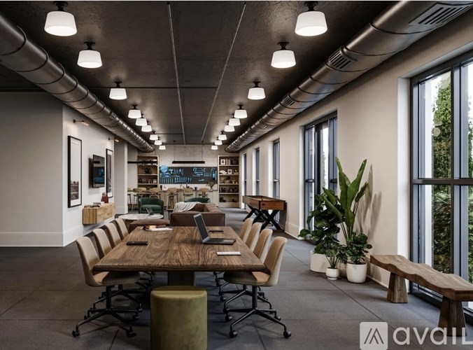 A conference room with a long table and chairs, a laptop on the table, and a plant on the side.