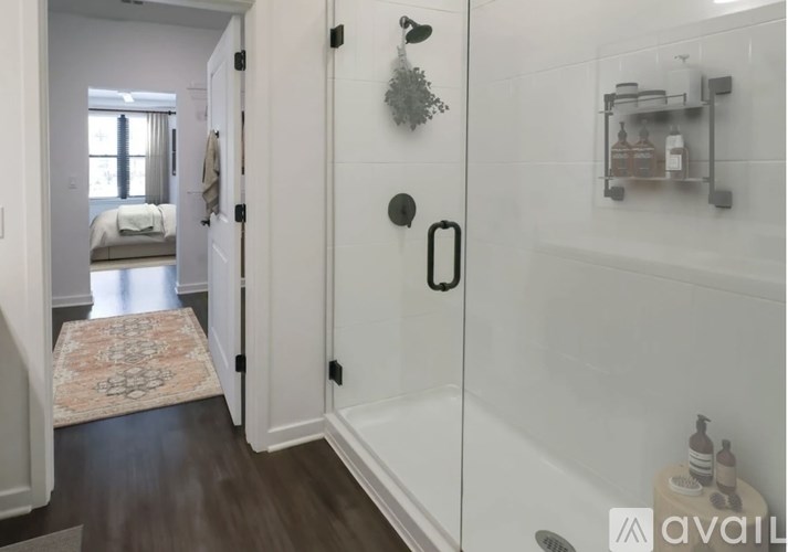A bathroom with a glass shower door and a rug on the floor.
