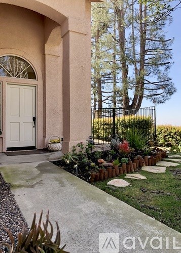A white door is on the left of a house with a garden in front.