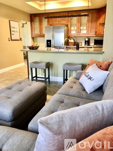 A kitchen with a bar stool and a couch with a pillow that says "love".