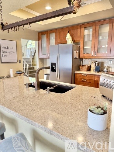 A kitchen with a bar stool and a couch with a pillow that says "love".