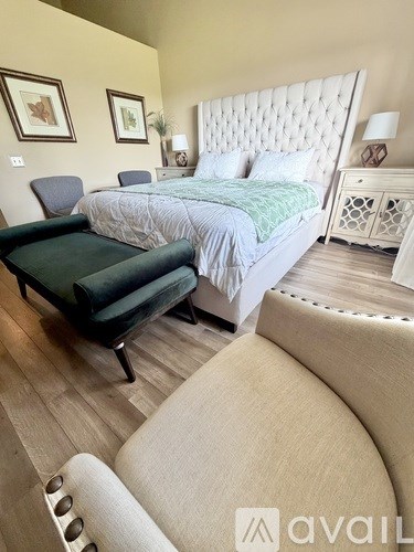 A bedroom with a large bed and a chair.