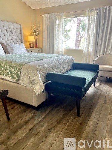 A bedroom with a large bed and a black chair.