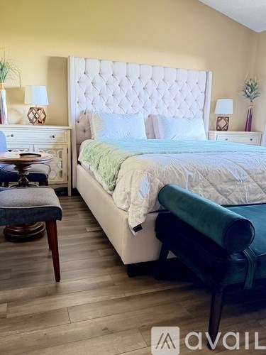 A bedroom with a bed, a bench, and a painting on the wall.