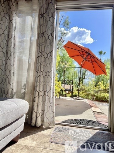 A bright orange umbrella is open and propped up against a building.