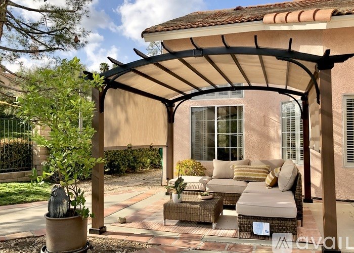 A patio with a couch and a table under a pergola.