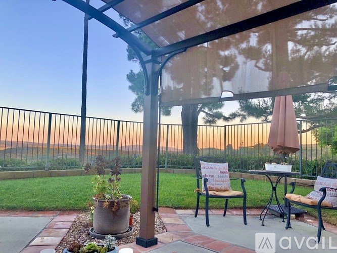 A patio with a table and chairs under a canopy with a sign that says "Home - for rent".
